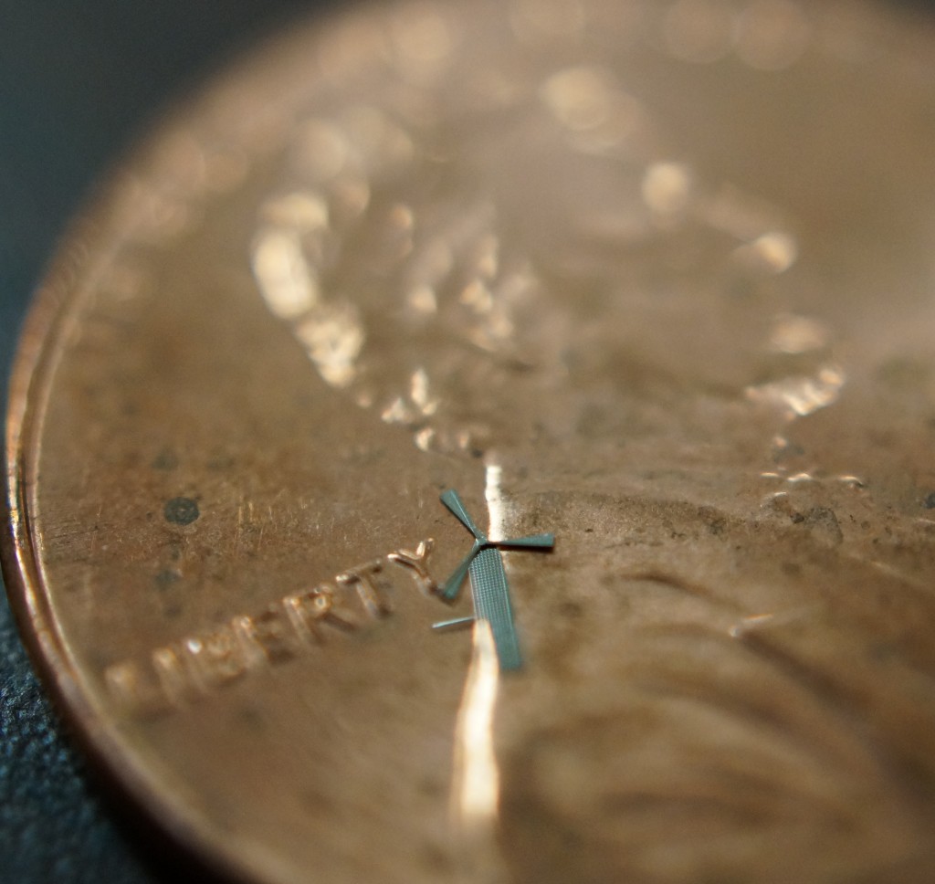 The tiny windmill sits on a penny.